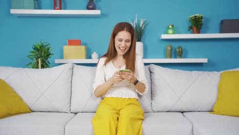 Young-woman-laughing-at-phone-message.